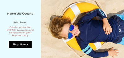 boy wearing a swimsuit and sunglasses on a beach wearing a kids rashguard
